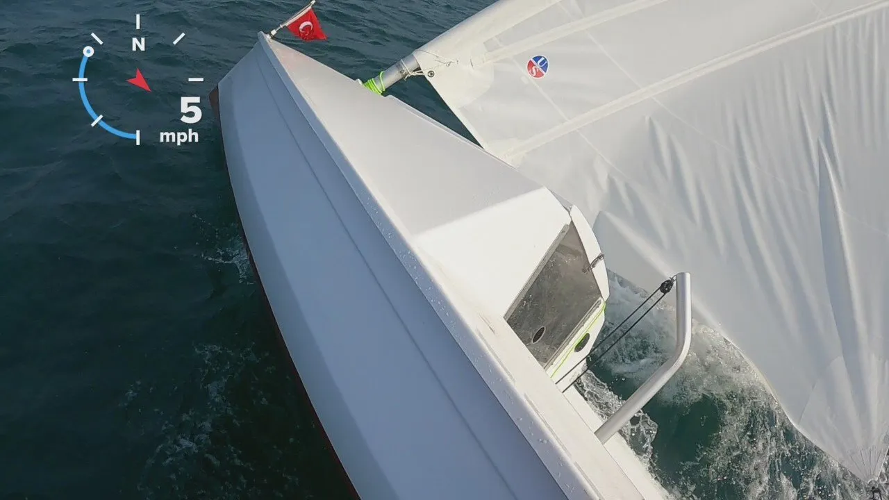 Heeled in a fresh breeze. Past about 45° the boomless rig spills wind on its own — she leans but doesn’t go over.